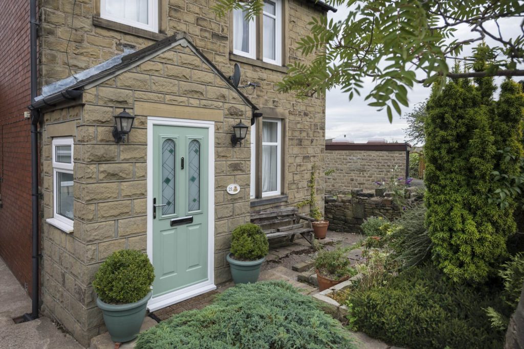 An impressive home featuring a blend of Chartwell green and stone exteriors, complemented by a stunning green composite front door. The house boasts a perfect balance of elegance and natural charm, providing a warm and welcoming ambiance.